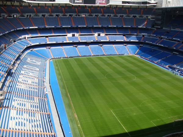 The Santiago Bernabéu stadium with green pitch and empty blue stands