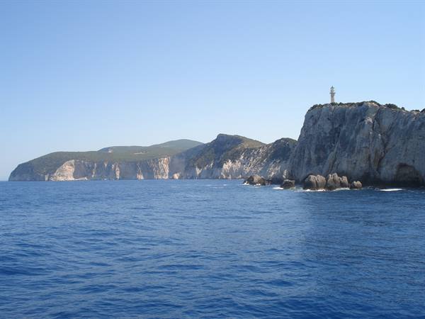 White lighthouse atop limestone cliffs plunging into deep blue sea