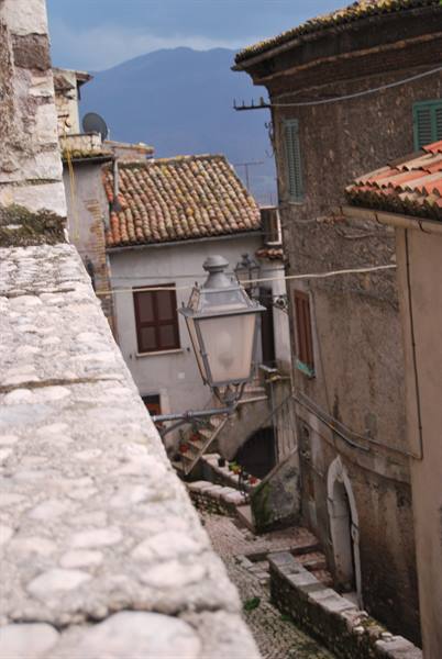 Iron lantern above a stone alley between medieval houses with tiled roofs