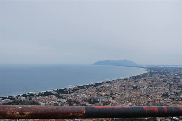 Coastal town beneath Monte Circeo seen over a rusty railing