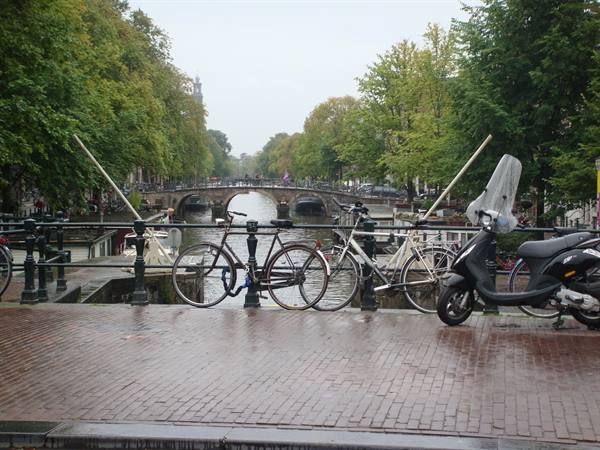 Bicycles and scooter parked on a brick bridge over Amsterdam canal