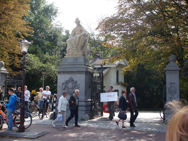 Pedestrians and bicycles by the stone gate with statue at Vondelpark