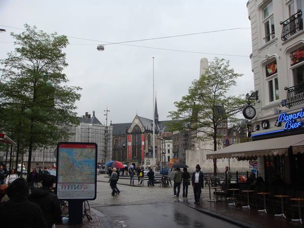 Tourists with umbrellas on Dam Square, Amsterdam, near the National Monument