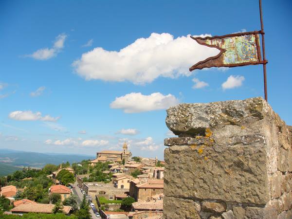 Iron flag on a stone wall above Montalcino's rooftops