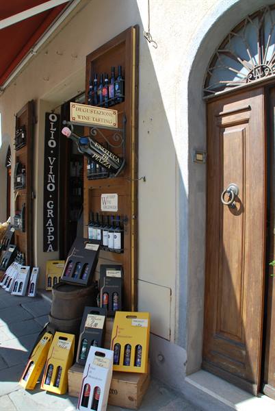 Wine shop in Montepulciano, bottles and wooden doors in sunlight