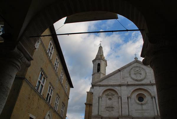 Pienza's travertine cathedral framed by the loggia arch