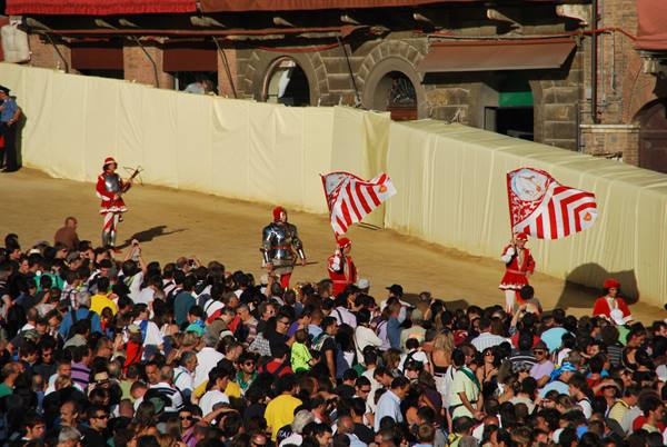 Flag bearers parading in red and white costumes at Siena's Palio