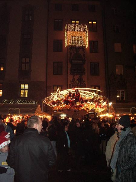 Illuminated Christmas market stall at night, crowd strolling, Munich