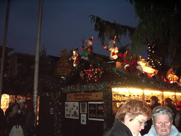 Bremen Christmas market: illuminated wooden stall with Santa figures, visitors strolling at night