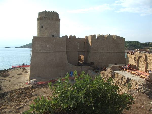 Round tower and stone walls of Le Castella castle facing the sea
