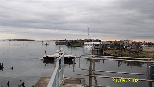 Fishing boats moored at a wooden pier in the lagoon, cloudy sky