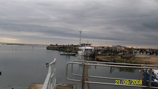 Boats moored at a metal jetty in the lagoon under cloudy skies