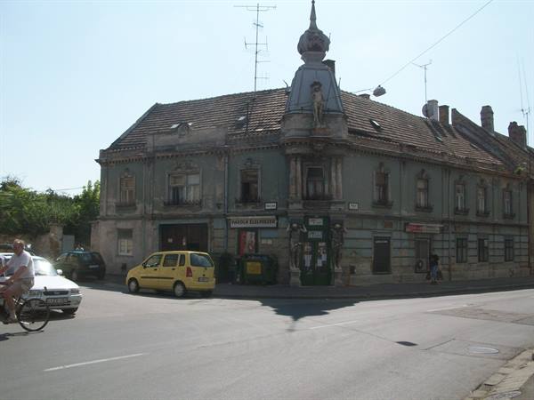 Cyclist at traffic light by old corner building with tiled roof