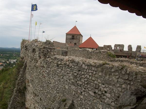 Stone castle walls with red-roofed tower and flags waving in the wind