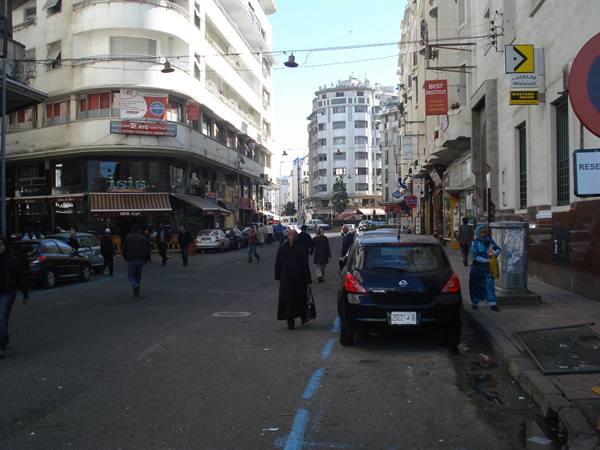 Pedestrians and parked cars on a city street among 1950s buildings, Casablanca
