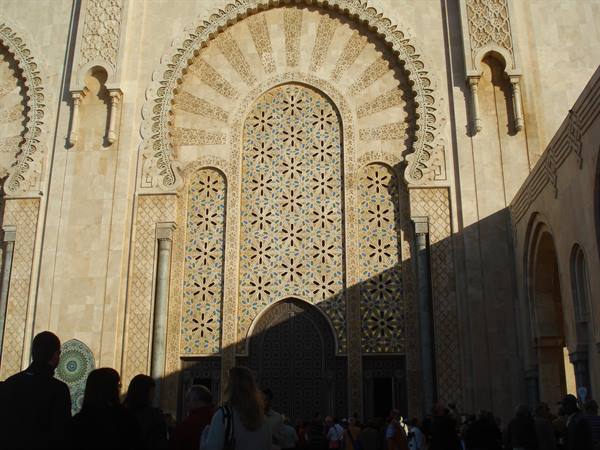 Tourists beneath the zellige-decorated arch of Hassan II Mosque in Casablanca