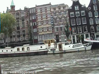 Tall canal houses in Amsterdam with boats moored on the water