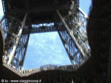 Iron lattice of the Eiffel Tower seen from below, blue sky between pillars