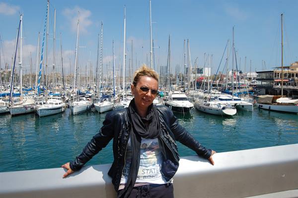 Woman in black jacket and scarf at the marina among sailboats and yachts