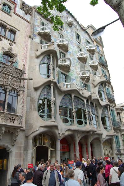 Tourists in front of Casa Batlló's undulating facade, sculpted balconies and colored glass
