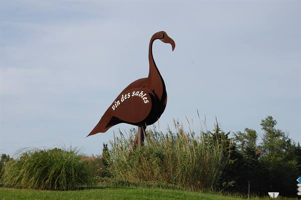 Metal flamingo sign 'Vin des sables' rising among reeds in the Camargue