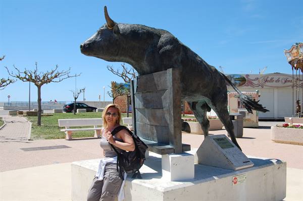 Woman with backpack next to the bronze bull statue under blue sky
