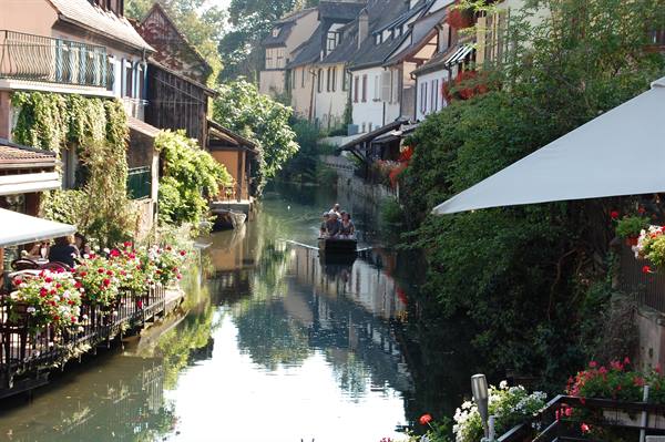 Tour boat on the Petite France canal in Colmar among timbered houses and flowers