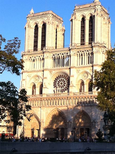 Gothic facade of Notre-Dame de Paris in warm evening sunlight
