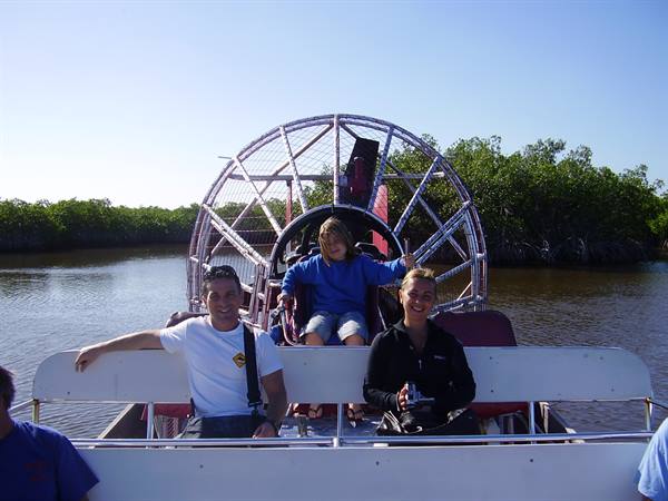 Tourists riding an airboat through Everglades mangroves, steel fan propeller behind