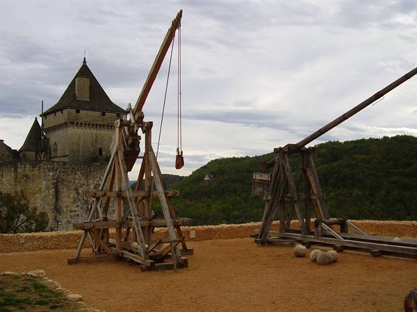 Wooden trebuchets and stone balls in front of Castelnaud castle