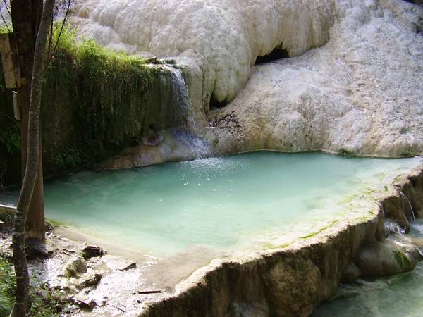 Bagni San Filippo: turquoise thermal pool among white travertine formations and small waterfall