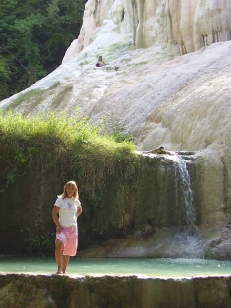 Woman in pink towel by travertine thermal cascades at Bagni San Filippo