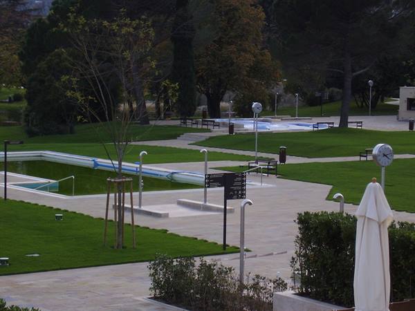 Empty pools on green lawn, clock on pole, soft evening light