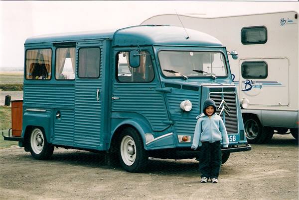 Child standing beside a blue Citroën H van converted into a camper