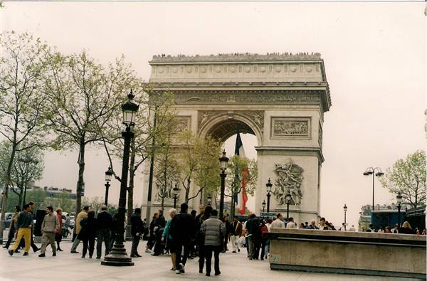 Tourists walk beneath the Arc de Triomphe in Paris on an overcast day