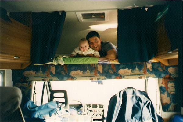 Father and baby smiling on the bunk bed inside the camper