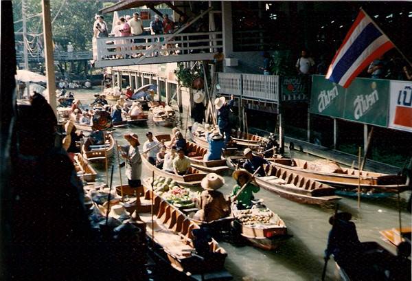 Damnoen Saduak floating market, wooden boats loaded with fruit, Thai flag waving