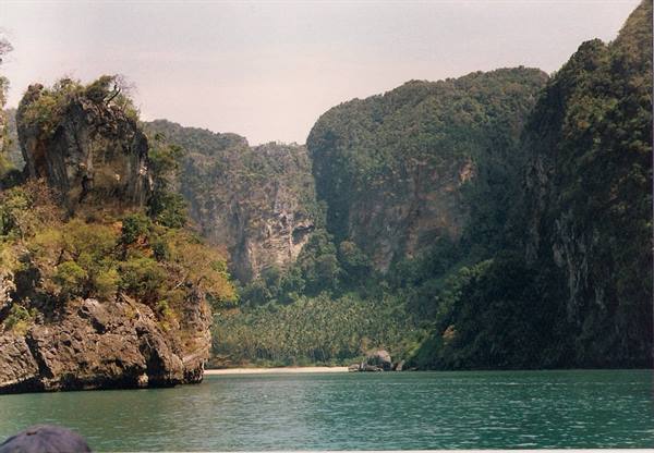 Limestone cliffs covered in jungle rise above turquoise-green water, Phang Nga Bay