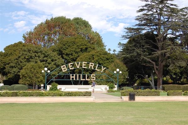 Beverly Hills metal sign in the park, green lawn, tall trees, daylight