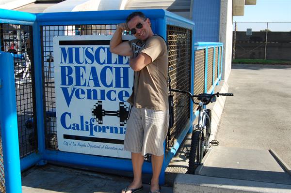 Man with bicycle next to the Muscle Beach sign in Venice, California