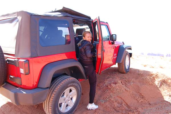 Woman getting out of a red Jeep on red sand