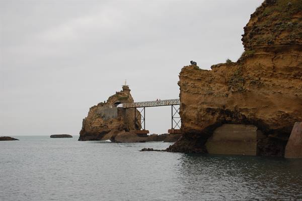 Metal footbridge crossing chalk cliffs of Étretat above the grey sea