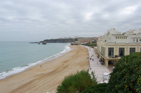 Sandy beach in front of Biarritz's Casino, people strolling under cloudy sky
