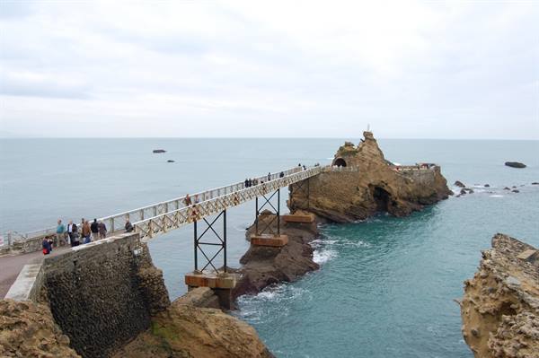 Tourists cross the metal footbridge to the Rocher de la Vierge in Biarritz