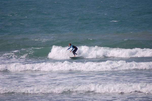 Surfer in black wetsuit rides a foamy wave on green sea