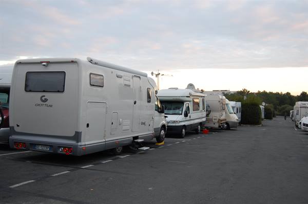White motorhomes parked on gray asphalt under cloudy morning sky