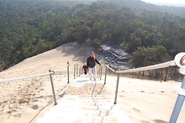 Tourist climbing the wooden staircase up the sand of Dune du Pilat
