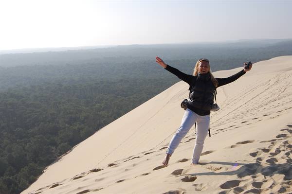 Woman with backpack, arms wide open on the sand of Dune du Pilat