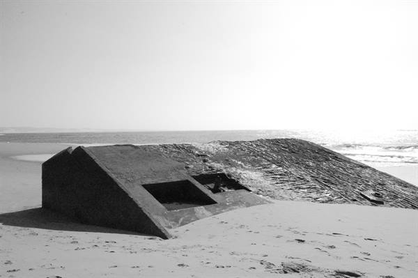 Abandoned concrete bunker on sandy beach, strong light, black and white