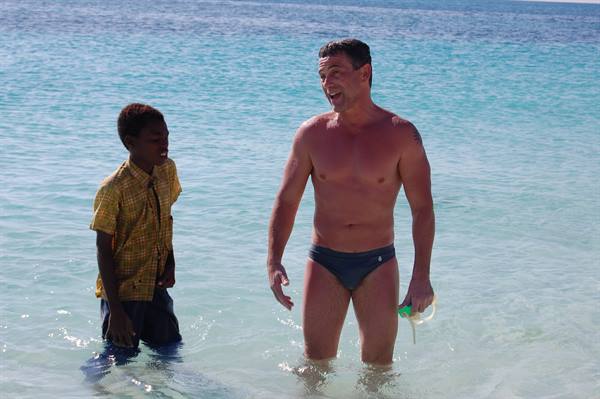 Man in swim trunks and boy laughing in turquoise sea water